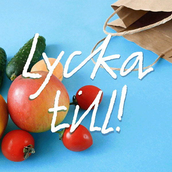 En papperskasse som fylls med olika frukter och grönsaker med texten 'Lycka till!' framför