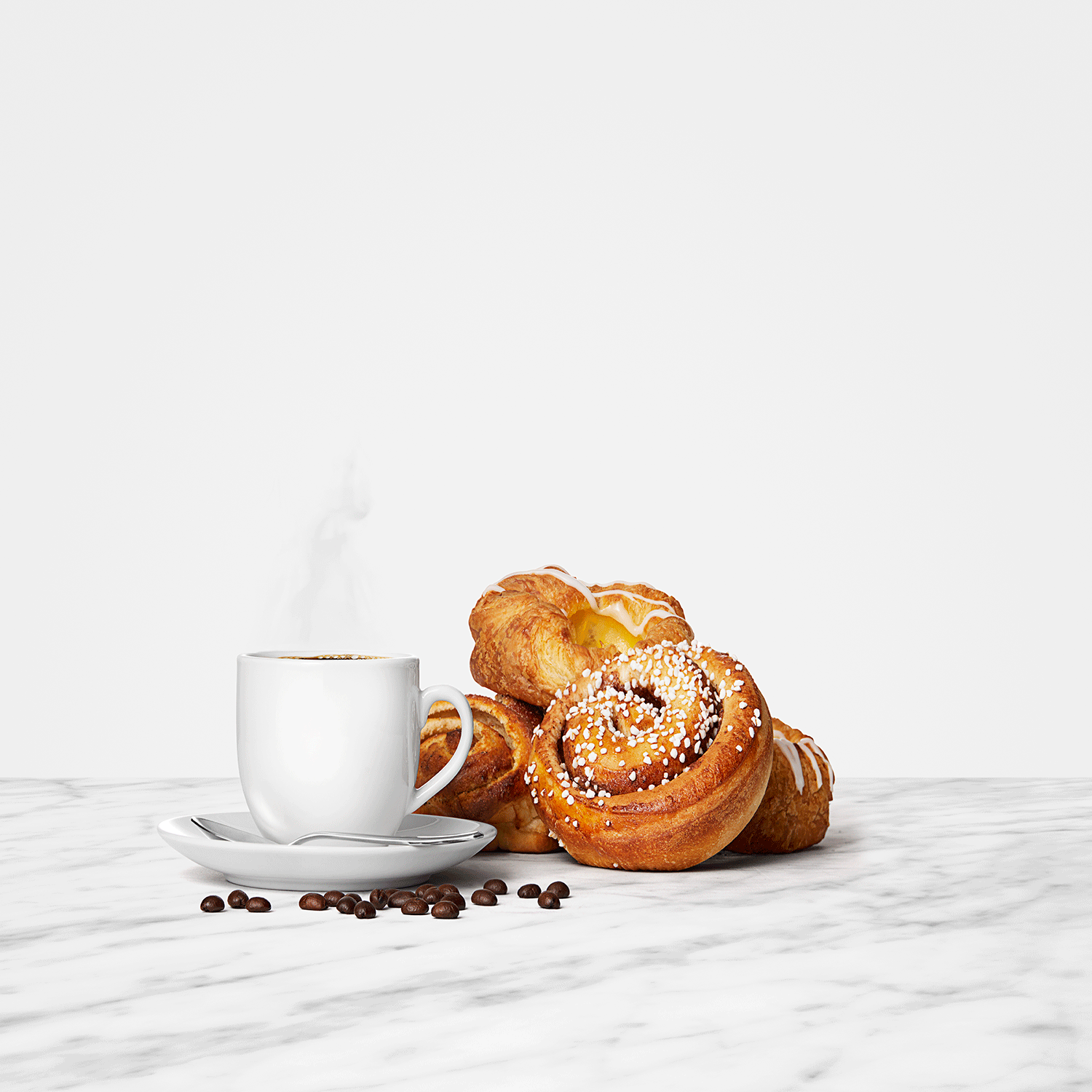 Kanelbulle och wienerbröd bredvid en kopp med rykande kaffe