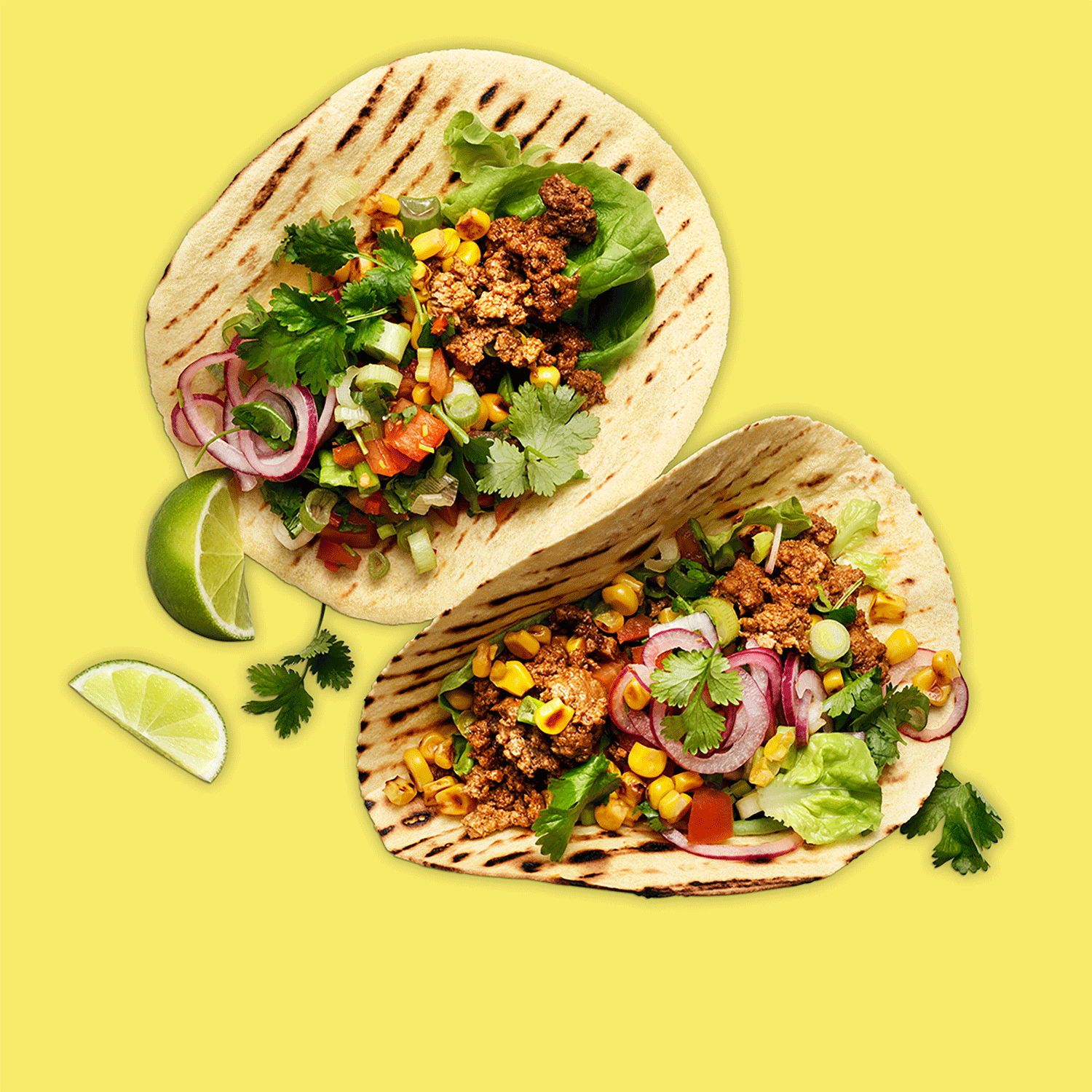 Två fyllda tacobröd med grönsaker och köttfärs samt två lime-klyftor varav den ena flyttar sig stegvis in och ut ur bild